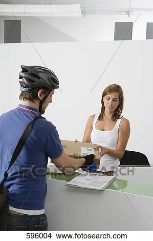 Picture - A bicycle courier handing a parcel to a receptionist. Fotosearch