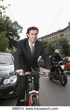 A businessman riding a bicycle on a city street View Large Photo Image Picture - A businessman riding a bicycle on a city street. Fotosearch