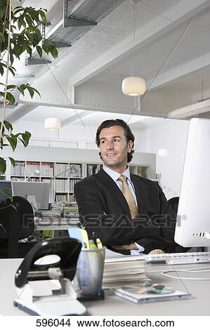 A businessman sitting at a desk in an office View Large Photo Image Picture - A businessman sitting at a desk in an office. Fotosearch
