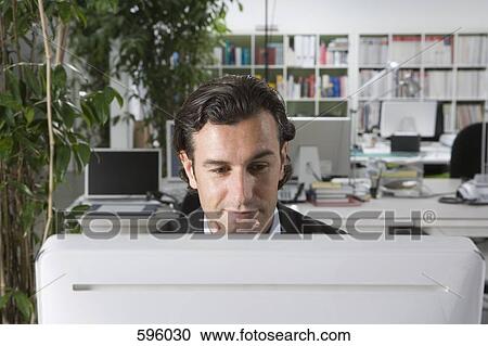 A businessman using a computer in an office View Large Photo Image Stock Image - A businessman using a computer in an office. Fotosearch