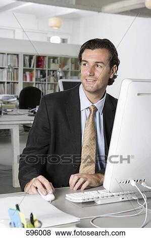 A businessman using a computer in an office View Large Photo Image Stock Photo - A businessman using a computer in an office. Fotosearch