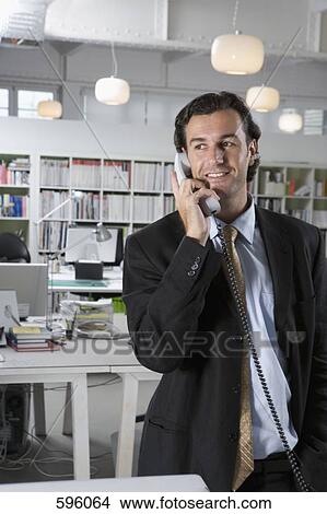 A businessman using a telephone in an office View Large Photo Image Picture - A businessman using a telephone in an office. Fotosearch