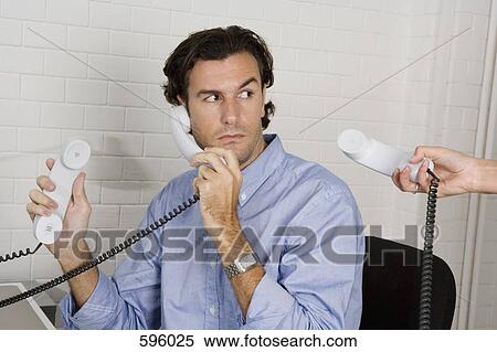 A businessman with three telephone receivers View Large Photo Image Stock Photography - A businessman with three telephone receivers. Fotosearch