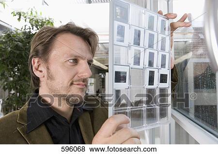 Stock Photo - A man looking at a contact sheet of slides. Fotosearch