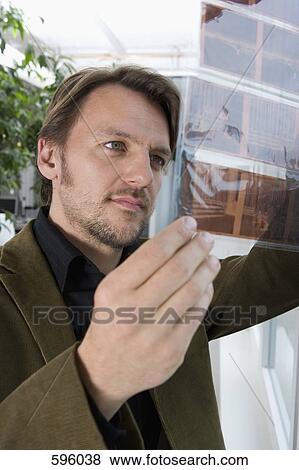 A man looking at a slide contact sheet View Large Photo Image Stock Photo - A man looking at a slide contact sheet. Fotosearch