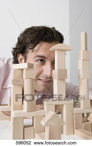 A man using wooden building blocks at a desk View Large Photo Image Stock Image - A man using wooden building blocks at a desk. Fotosearch