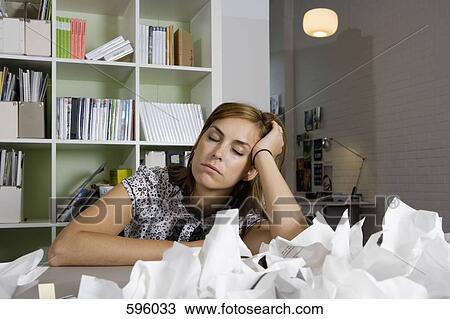 A woman sitting at a desk behind a pile of screwed up paper View Large Photo Image Stock Image - A woman sitting at a desk behind a pile of screwed up paper. Fotosearch
