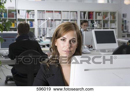 A woman sitting behind a computer in an office View Large Photo Image Stock Photo - A woman sitting behind a computer in an office. Fotosearch