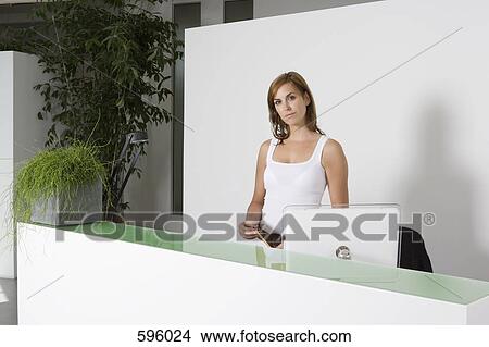 A woman standing behind an office reception desk View Large Photo Image Picture - A woman standing behind an office reception desk. Fotosearch