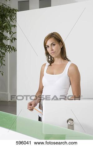 A woman standing behind an office reception desk View Large Photo Image Stock Image - A woman standing behind an office reception desk. Fotosearch