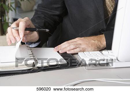 Detail of a businessman using a personal organizer at his desk View Large Photo Image Stock Image - Detail of a businessman using a personal organizer at his desk. Fotosearch