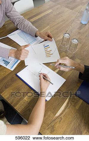 Detail of three people looking at documents in a business meeting View Large Photo Image Stock Image - Detail of three people looking at documents in a business meeting. Fotosearch