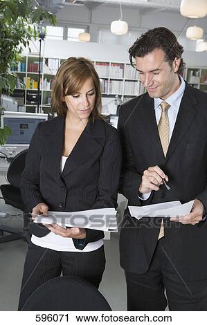 Office colleagues looking over documents together View Large Photo Image Stock Image - Office colleagues looking over documents together. Fotosearch