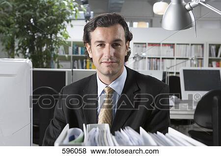 Portrait of a businessman sitting at a desk View Large Photo Image Stock Photo - Portrait of a businessman sitting at a desk. Fotosearch