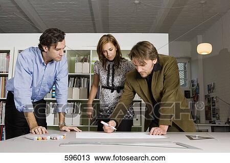 Stock Image - Three people brainstorming in an office. Fotosearch