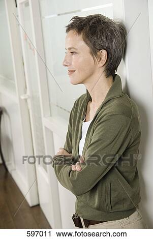 A Smiling Mature Woman leaning against a wall with her arms crossed View Large Photo Image Stock Image - A Smiling Mature Woman leaning against a wall with her arms crossed. Fotosearch