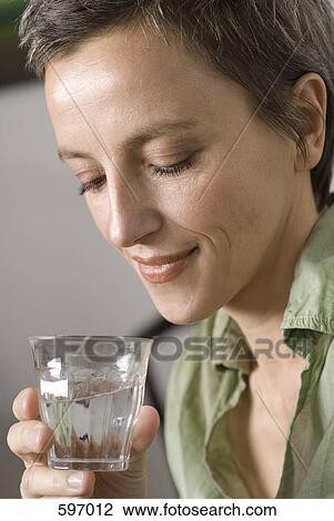 Stock Image - A smiling mature woman looking into a glass of water. Fotosearch