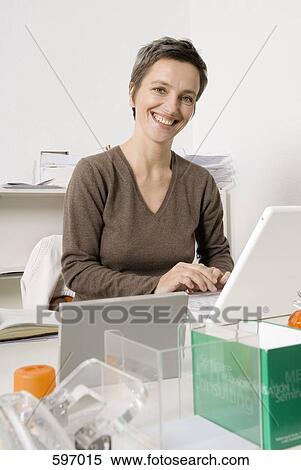 A smiling Mature woman typing on a laptop View Large Photo Image Stock Photography - A smiling Mature woman typing on a laptop. Fotosearch