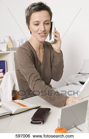 A Smiling Mature Woman using a cordless phone View Large Photo Image Stock Photograph - A Smiling Mature Woman using a cordless phone. Fotosearch