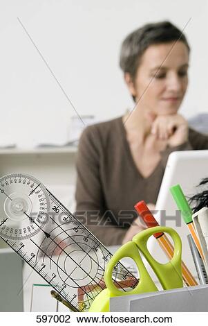 Close up of office supplies with Mature Woman working in the background View Large Photo Image Stock Image - Close up of office supplies with Mature Woman working in the background. Fotosearch