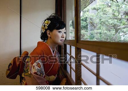 Stock Photo - A woman wearing a kimono and looking out of a window. Fotosearch