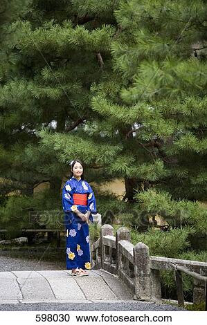 Stock Image - A woman wearing a kimono standing on a bridge. Fotosearch