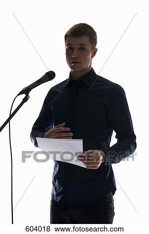 A young man giving a speech into a microphone View Large Photo Image Stock Photo - A young man giving a speech into a microphone. Fotosearch