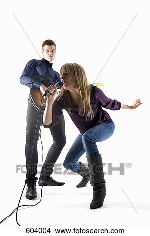 Studio shot of a man playing electric guitar and a woman singing into a microphone View Large Photo Image Picture - Studio shot of a man playing electric guitar and a woman singing into a microphone. Fotosearch