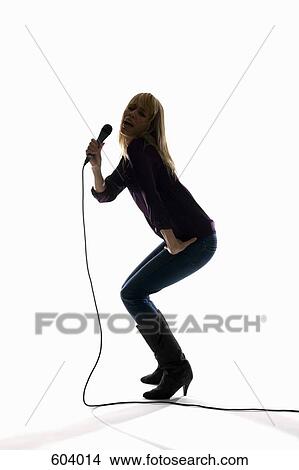 Studio shot of a woman singing into a microphone View Large Photo Image Picture - Studio shot of a woman singing into a microphone. Fotosearch