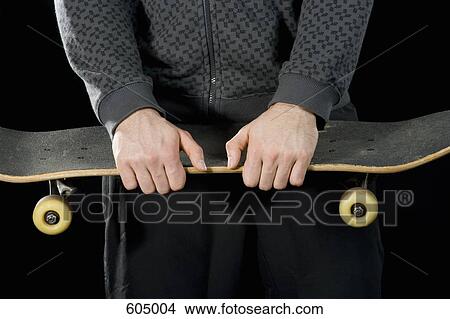 A young man holding a skateboard View Large Photo Image Picture - A young man holding a skateboard. Fotosearch