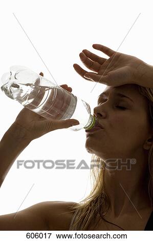 A sweating woman drinking from a water bottle View Large Photo Image Stock Photo - A sweating woman drinking from a water bottle. Fotosearch