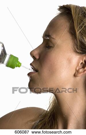 Stock Photo - A sweating woman drinking from a water bottle. Fotosearch