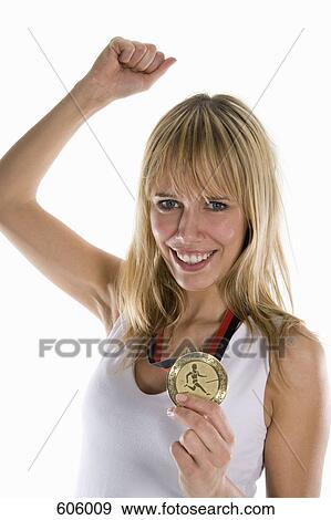 A woman holding a gold medal and raising her fist in celebration View Large Photo Image Stock Photo - A woman holding a gold medal and raising her fist in celebration. Fotosearch
