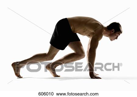 Stock Image - Studio shot of a male runner preparing to race. Fotosearch