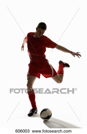 Stock Image - Studio shot of a soccer player kicking a soccer ball. Fotosearch