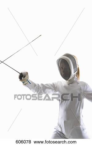 Stock Photo - Studio shot of female fencer posing with a fencing foil in a confrontation with another fencing foil. Fotosearch