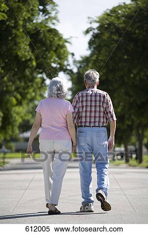 A senior couple walking along a street View Large Photo Image Stock Photography - A senior couple walking along a street. Fotosearch