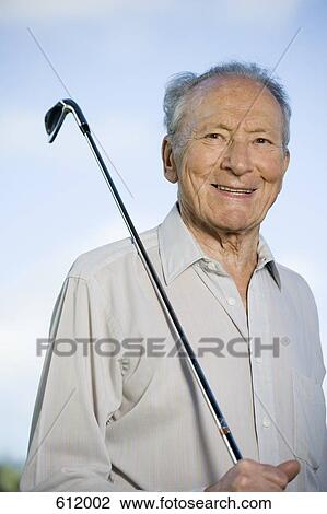 Stock Image - A senior man holding a golf club. Fotosearch