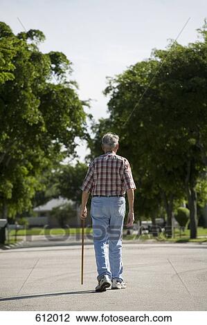 A senior man walking along a street View Large Photo Image Stock Image - A senior man walking along a street. Fotosearch