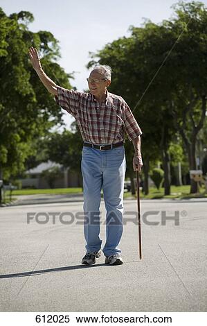 Stock Photography - A senior man walking in the street and waving. Fotosearch