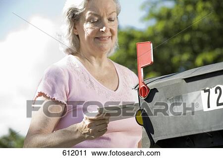 Stock Image - A senior woman checking the mailbox. Fotosearch