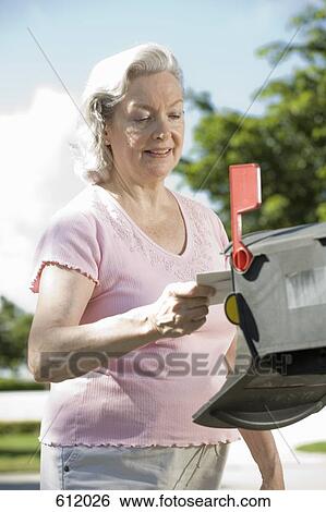 Stock Photograph - A senior woman checking the mailbox. Fotosearch