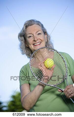 A senior woman holding a tennis racket and ball View Large Photo Image Stock Photo - A senior woman holding a tennis racket and ball. Fotosearch