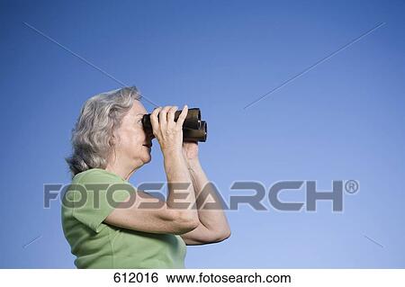 Stock Photograph - A senior woman looking through binoculars. Fotosearch
