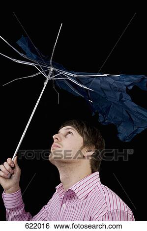 A man holding a broken umbrella View Large Photo Image Stock Photograph - A man holding a broken umbrella. Fotosearch