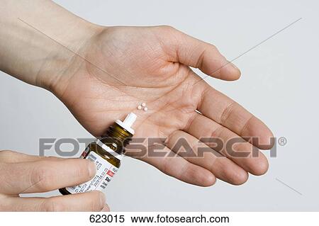 Stock Photography - A hand holding homeopathic medicine. Fotosearch