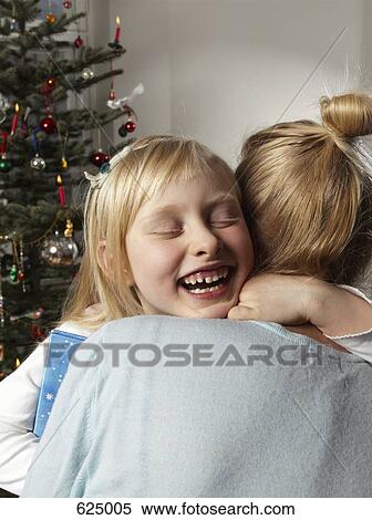 A girl embracing a woman next to a Christmas tree View Large Photo Image Stock Photography - A girl embracing a woman next to a Christmas tree. Fotosearch