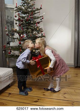 Two children kissing in front of a Christmas tree View Large Photo Image Stock Photo - Two children kissing in front of a Christmas tree. Fotosearch