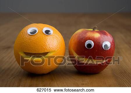 Stock Photography - An apple and an orange with plastic eyeballs. Fotosearch