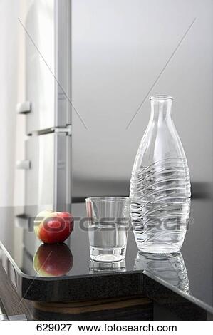 A carafe of water, a glass and an apple on a counter View Large Photo Image Stock Photo - A carafe of water, a glass and an apple on a counter. Fotosearch